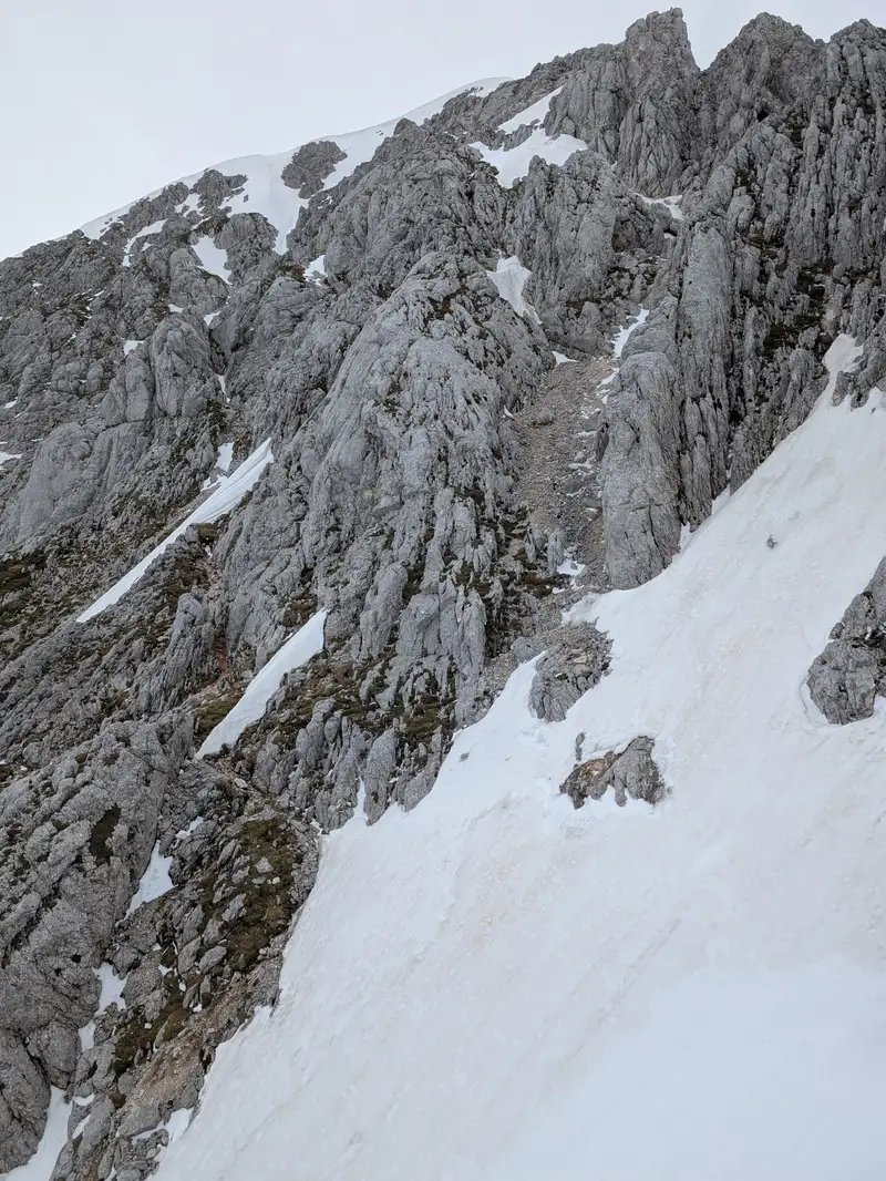 We leave Dolge stene ridge and enter Grintovec. The path runs somewhere through that snowy field and enter in the lower part (not the crumbly gully above). There are lots of cairns to help find the right way.